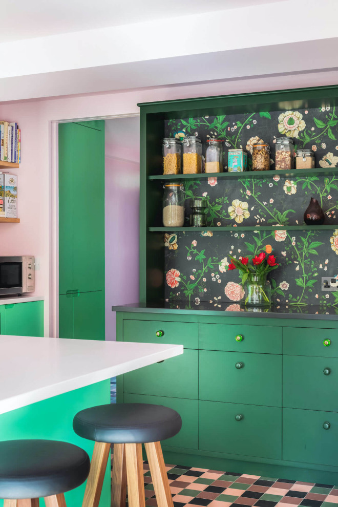 Photo of a mid-sized eclectic single-wall eat-in kitchen in London with flat-panel cabinets, green cabinets, solid surface benchtops, with island and white benchtop.