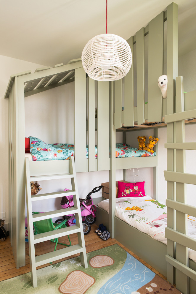 This is an example of a small transitional gender-neutral kids' bedroom for kids 4-10 years old in Nantes with beige walls and light hardwood floors.