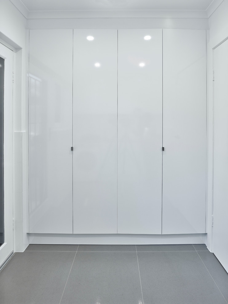 This is an example of a mid-sized contemporary single-wall dedicated laundry room with a drop-in sink, white cabinets, laminate benchtops, white walls and a side-by-side washer and dryer.