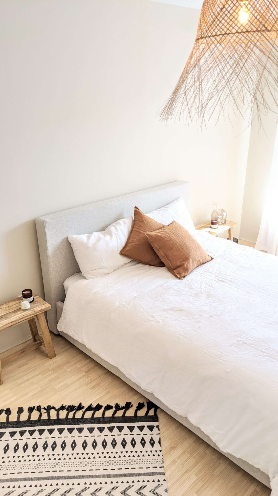 Ejemplo de dormitorio principal moderno de tamaño medio con paredes beige y suelo de madera clara