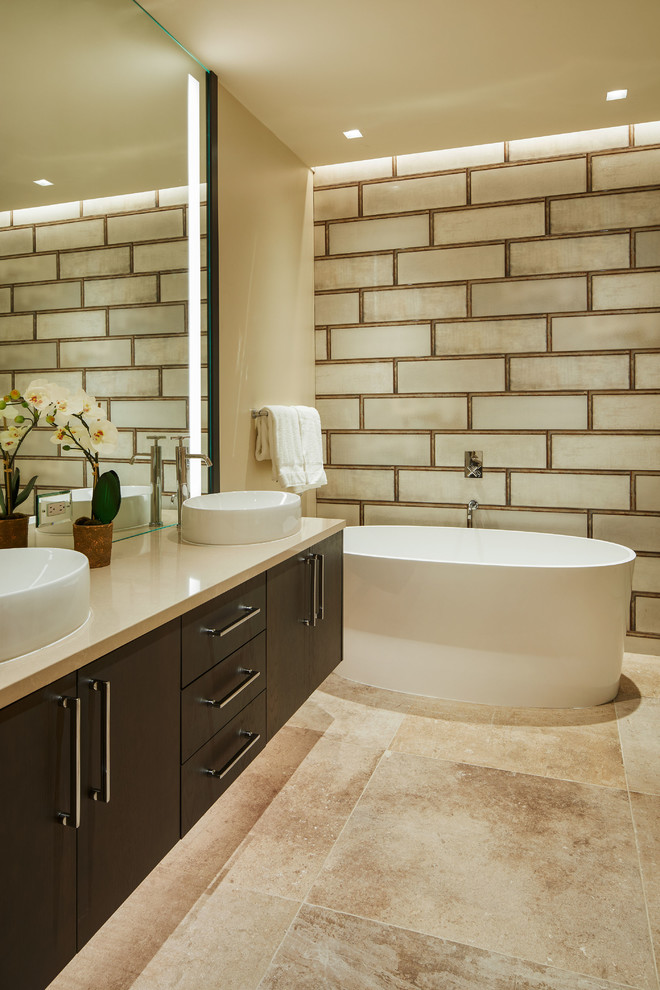 Mid-sized country bathroom in Denver with flat-panel cabinets, dark wood cabinets, beige tile, porcelain tile, a vessel sink, beige benchtops, a freestanding tub, beige walls, beige floor, a one-piece toilet and concrete floors.