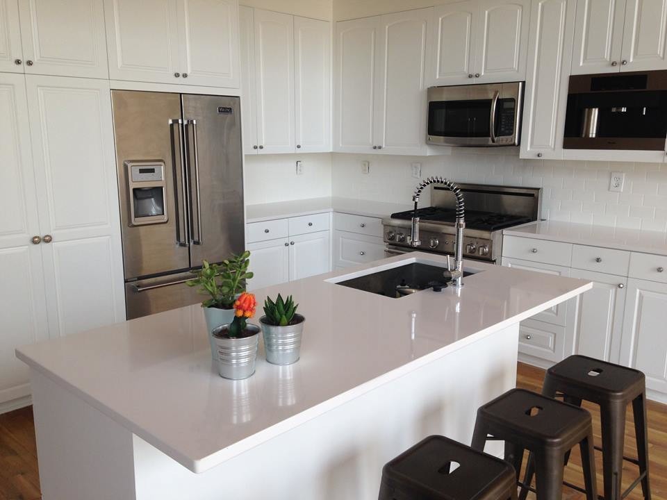 Example of a mid-sized transitional l-shaped light wood floor and brown floor open concept kitchen design in Austin with an undermount sink, raised-panel cabinets, white cabinets, stainless steel appliances, an island, white countertops, quartz countertops, white backsplash and subway tile backsplash