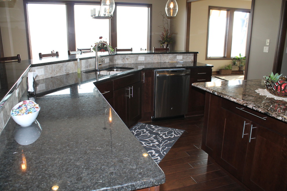 Open concept kitchen - large single-wall dark wood floor open concept kitchen idea with an undermount sink, flat-panel cabinets, dark wood cabinets, granite countertops, beige backsplash, stainless steel appliances, beige walls and two islands