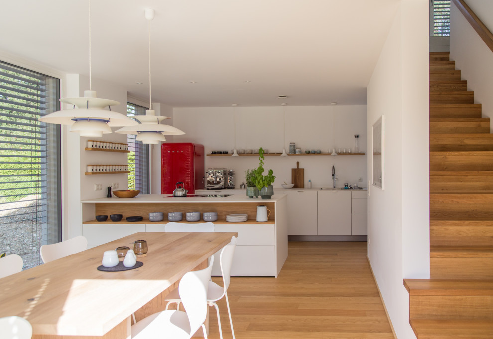 Contemporary open plan dining in Munich with white walls and medium hardwood floors.