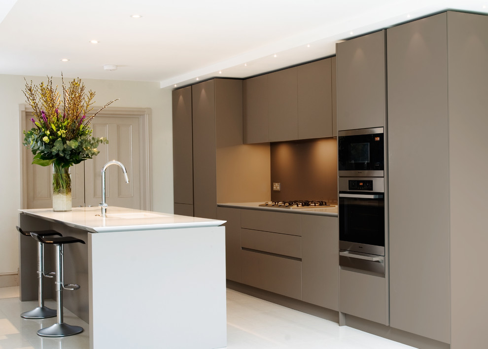 Mid-sized contemporary eat-in kitchen in London with an undermount sink, flat-panel cabinets, beige cabinets, quartz benchtops, beige splashback, stainless steel appliances, with island, glass sheet splashback and white floor.