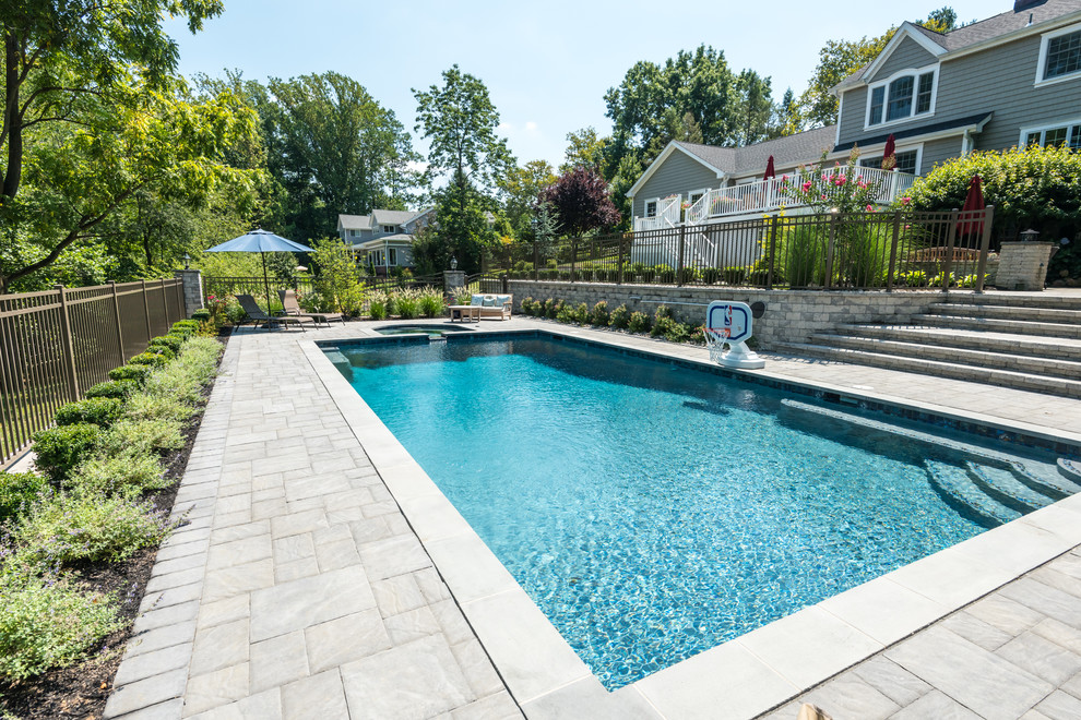 Large modern backyard rectangular natural pool in New York with a hot tub and brick pavers.
