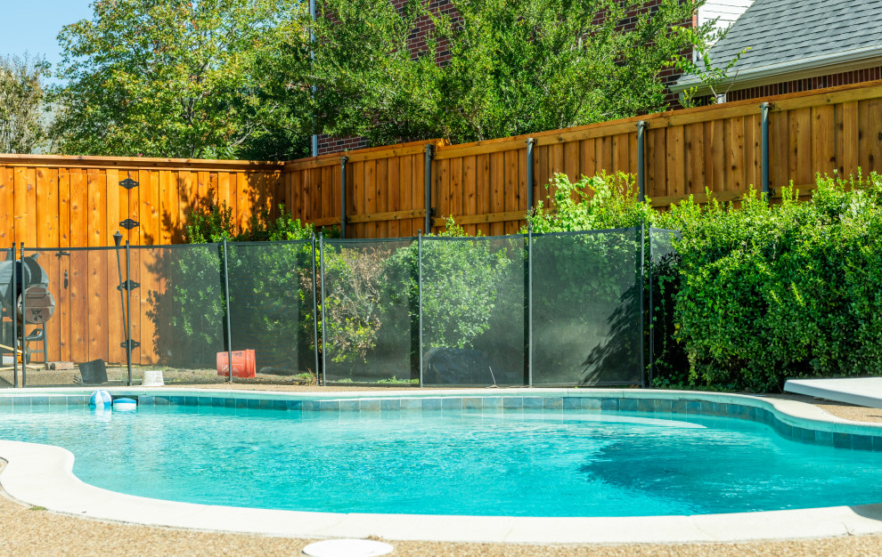 This is an example of a large traditional backyard garden in Dallas with a wood fence.
