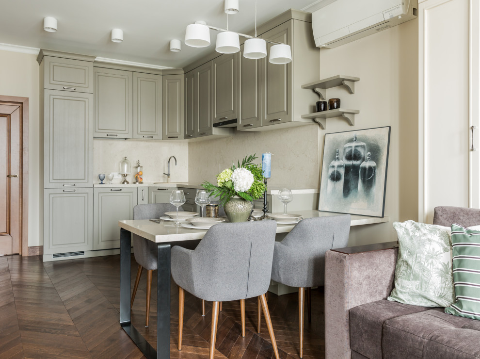 This is an example of a transitional u-shaped open plan kitchen in Moscow with raised-panel cabinets, grey cabinets, beige splashback, panelled appliances, medium hardwood floors, a peninsula and beige benchtop.