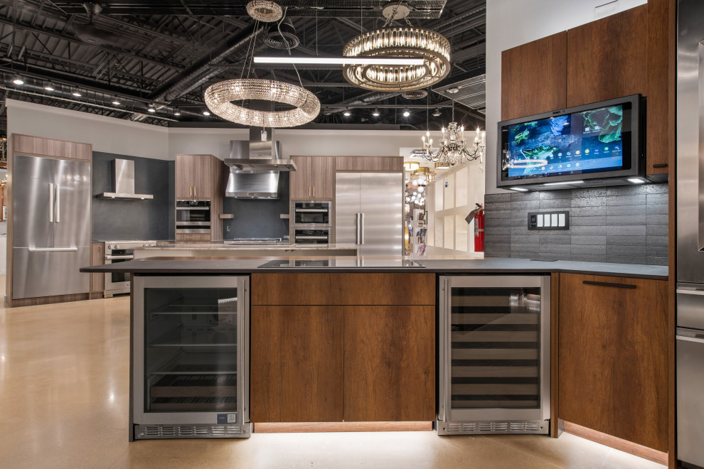 This is an example of a mid-sized contemporary l-shaped open plan kitchen in Austin with an undermount sink, flat-panel cabinets, medium wood cabinets, black splashback, stainless steel appliances, with island, beige floor and beige benchtop.