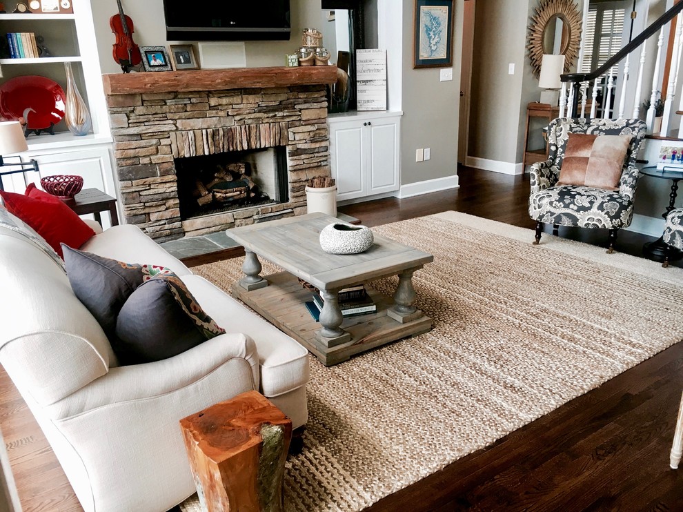 Photo of a mid-sized country open concept living room in Charlotte with dark hardwood floors, a stone fireplace surround, a wall-mounted tv, grey walls, a standard fireplace and brown floor.