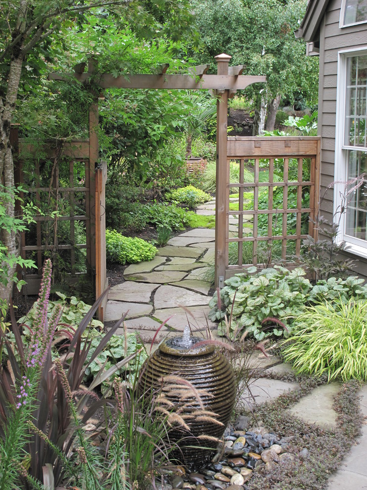 This is an example of a mid-sized traditional side yard shaded formal garden in Portland with a water feature and concrete pavers.