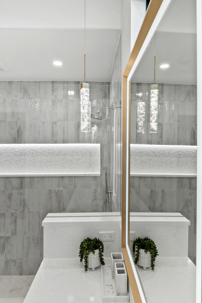 Example of a transitional master gray tile and porcelain tile porcelain tile, white floor and double-sink walk-in shower design with shaker cabinets, light wood cabinets, a two-piece toilet, white walls, an undermount sink, quartz countertops, white countertops, a niche and a built-in vanity
