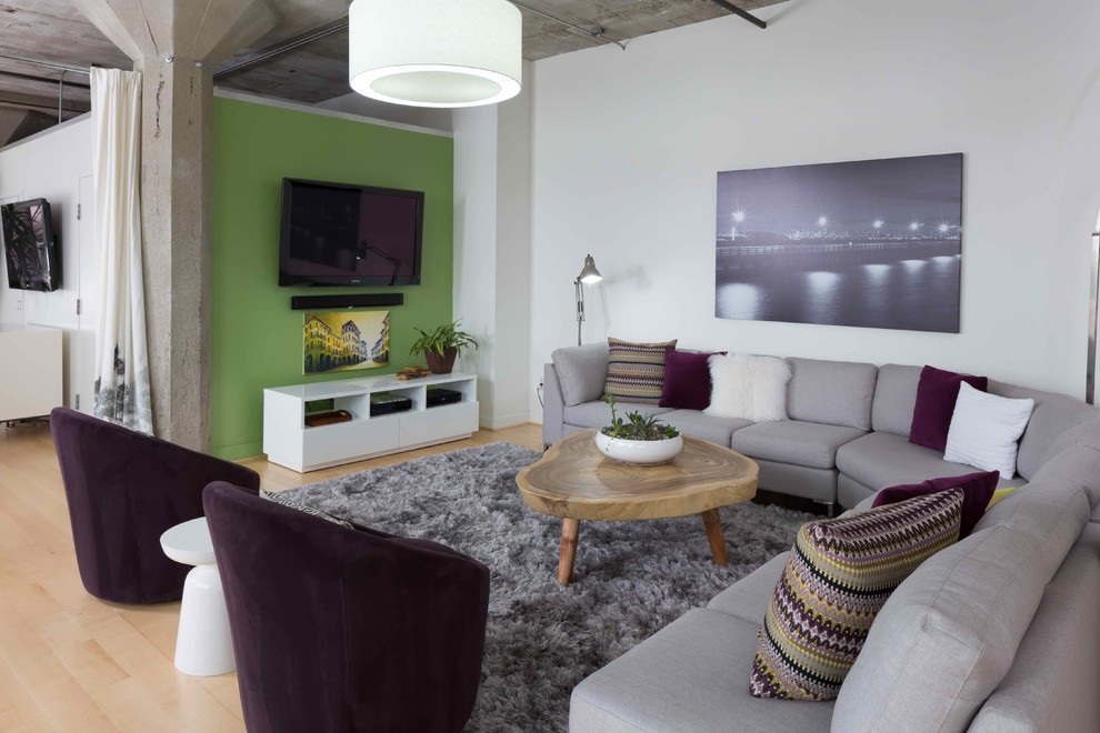 Industrial loft-style living room in San Francisco with green walls, light hardwood floors and a wall-mounted tv.