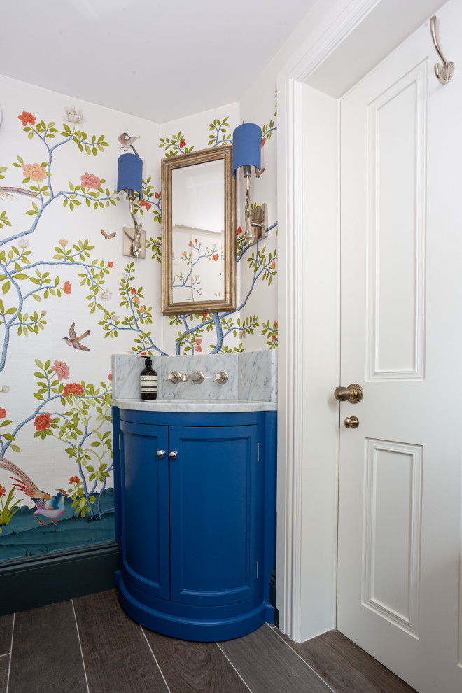 Design ideas for a classic cloakroom in London with recessed-panel cabinets, blue cabinets, multi-coloured walls, dark hardwood flooring, a submerged sink, marble worktops, brown floors, grey worktops, a built in vanity unit and wallpapered walls.