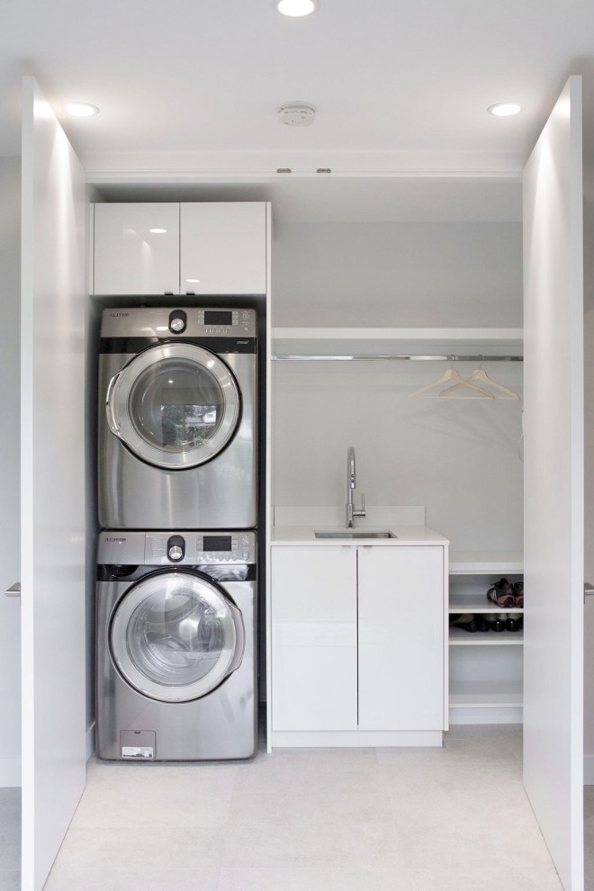 Inspiration for a small midcentury laundry cupboard in Vancouver with an undermount sink, flat-panel cabinets, white cabinets, quartz benchtops, porcelain floors, a stacked washer and dryer, grey floor and white benchtop.