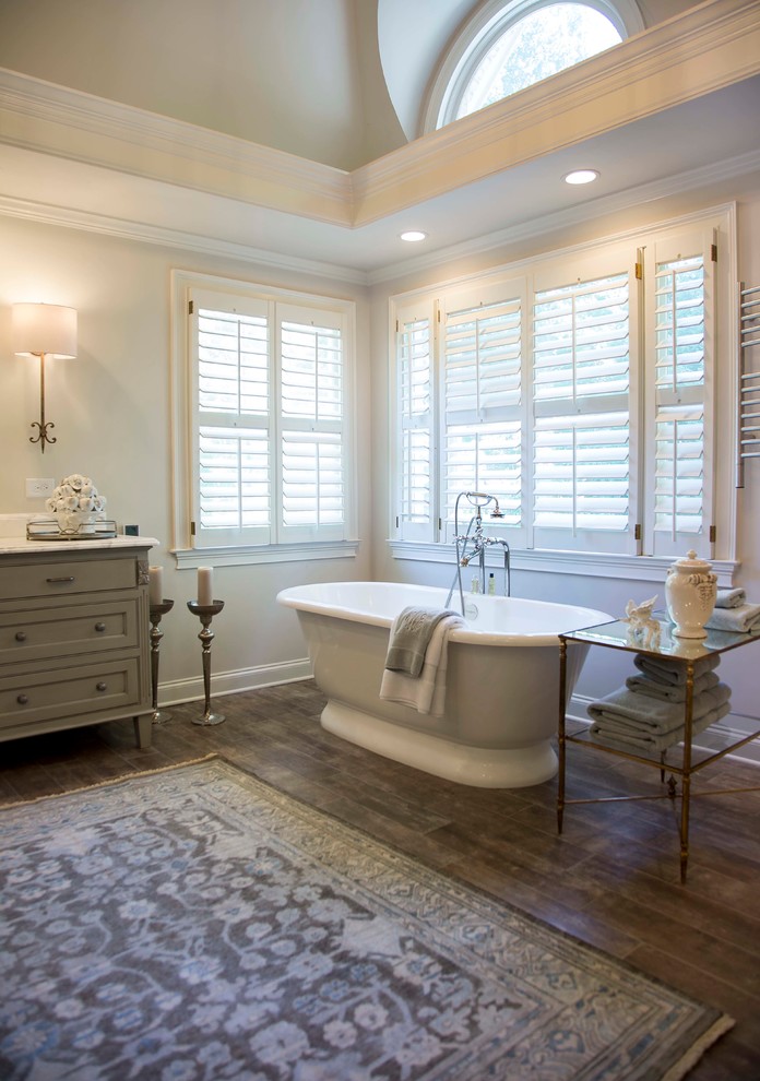Photo of a traditional bathroom in Atlanta with grey cabinets, a freestanding tub, dark hardwood floors and beaded inset cabinets.