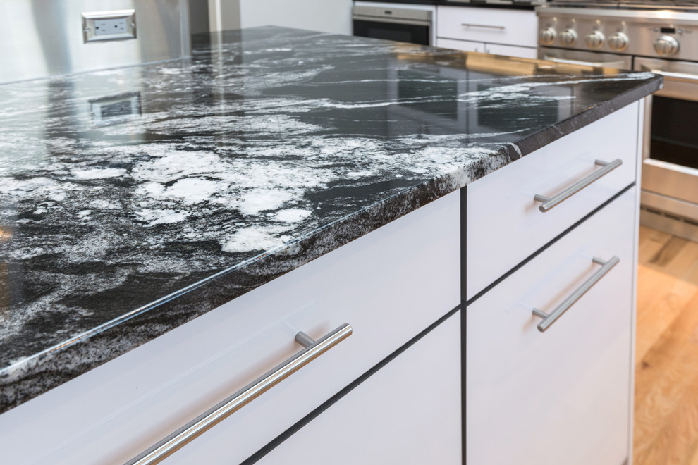 Inspiration for a large contemporary u-shaped light wood floor open concept kitchen remodel with an undermount sink, flat-panel cabinets, white cabinets, granite countertops, multicolored backsplash, mosaic tile backsplash, stainless steel appliances and an island
