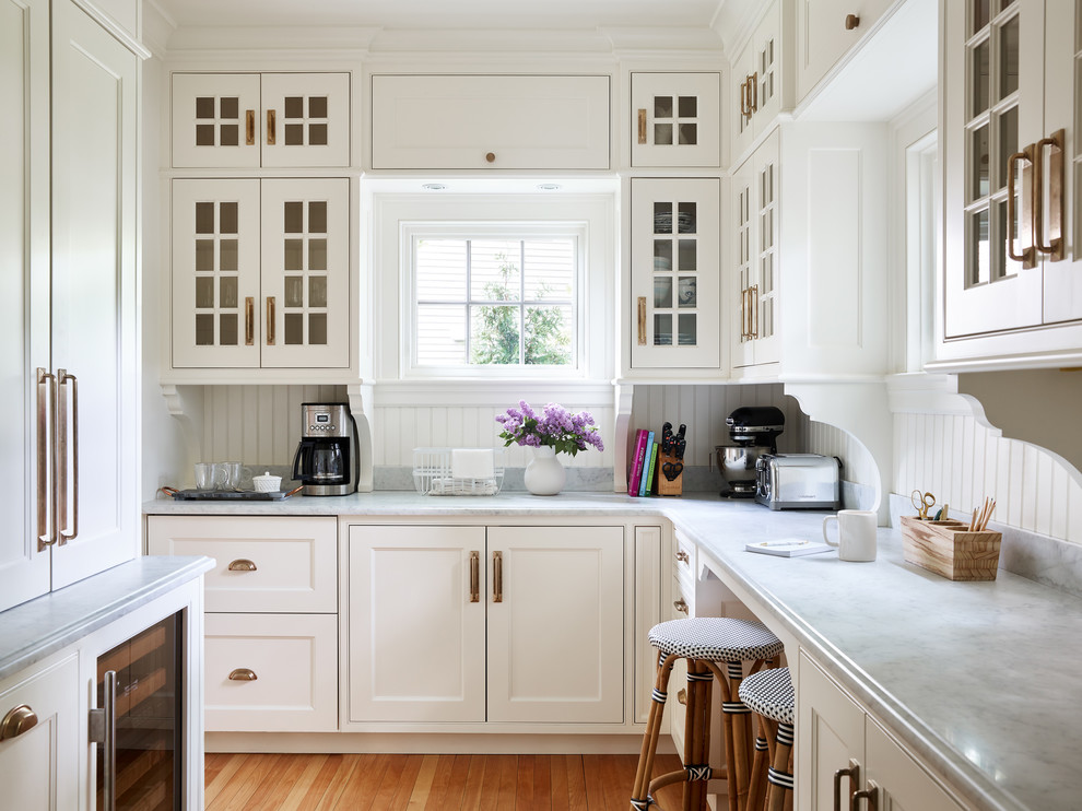 Large traditional l-shaped separate kitchen in Boston with glass-front cabinets, white cabinets, marble benchtops, white splashback, marble splashback, panelled appliances, medium hardwood floors, brown floor and grey benchtop.