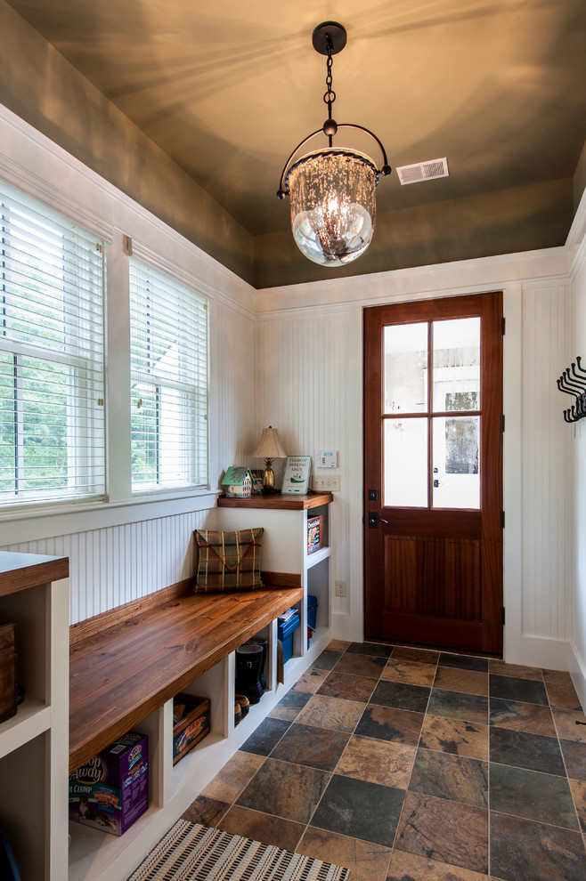 This is an example of a mid-sized traditional mudroom in Charleston with travertine floors, a medium wood front door, white walls and a single front door.