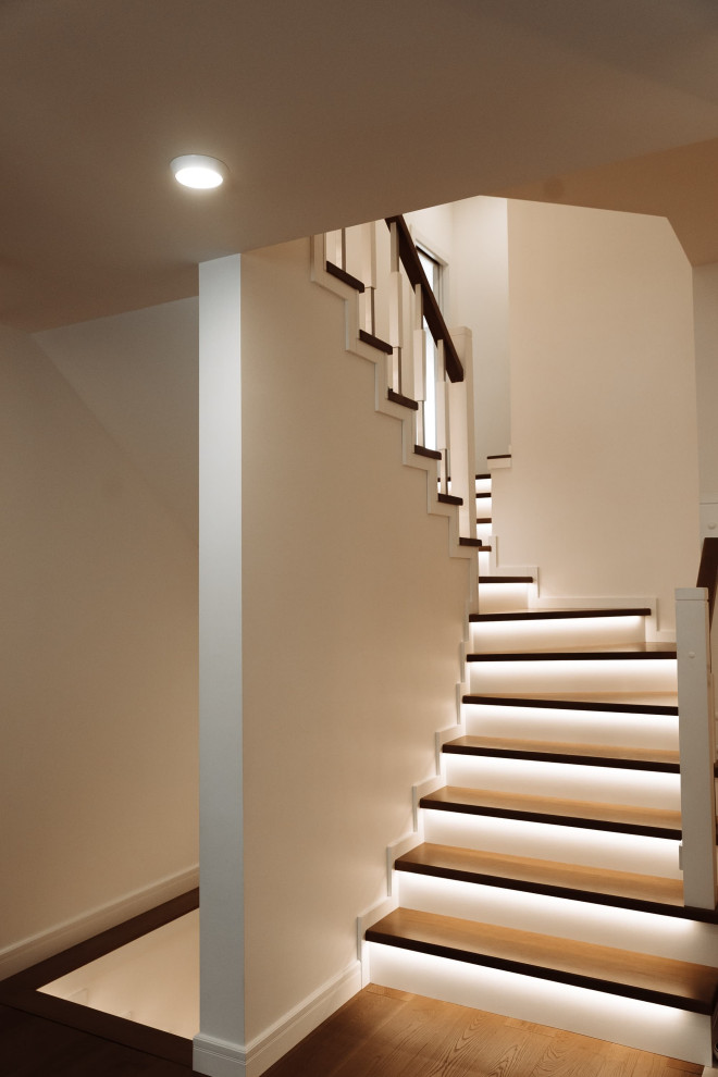 Modelo de escalera curva contemporánea grande con escalones de madera, contrahuellas de madera, barandilla de metal y ladrillo