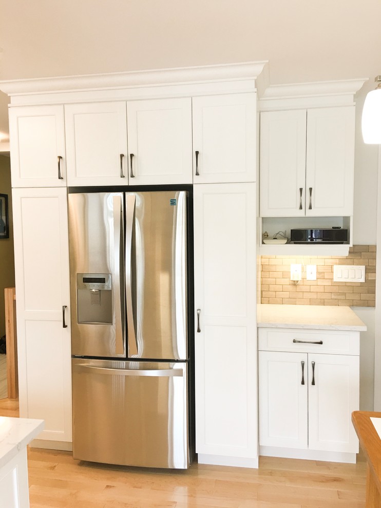 Eat-in kitchen - mid-sized contemporary u-shaped light wood floor and brown floor eat-in kitchen idea with a single-bowl sink, shaker cabinets, white cabinets, quartz countertops, beige backsplash, marble backsplash, stainless steel appliances and no island
