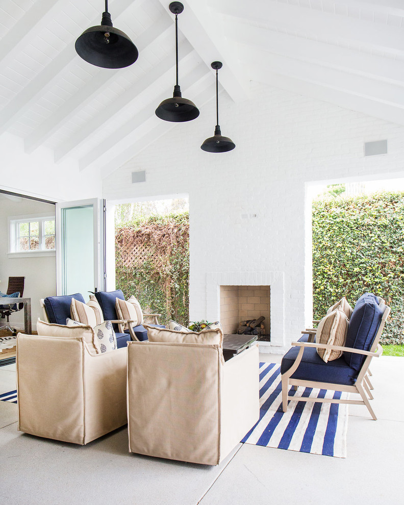 Beach style patio in Orange County with a roof extension, concrete slab and with fireplace.