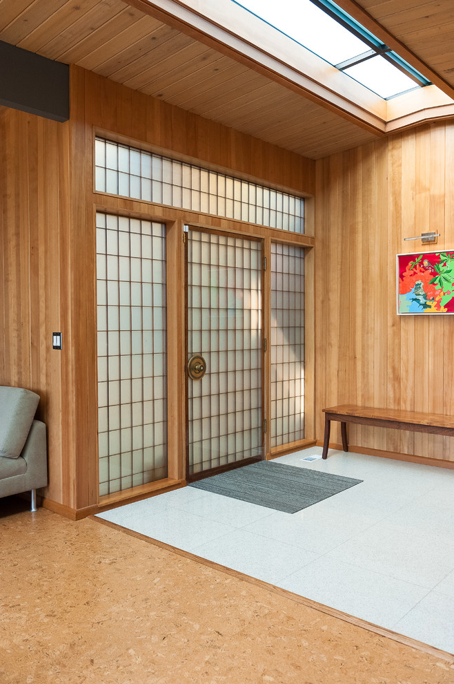 This is an example of a mid-sized midcentury foyer in Portland with terrazzo floors, a single front door, a medium wood front door, grey floor, vaulted and wood walls.