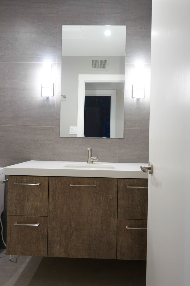 Photo of a mid-sized contemporary 3/4 bathroom in San Francisco with flat-panel cabinets, brown cabinets, an alcove tub, a shower/bathtub combo, a two-piece toilet, white tile, porcelain tile, brown walls, porcelain floors, an undermount sink, engineered quartz benchtops, grey floor, a shower curtain and white benchtops.