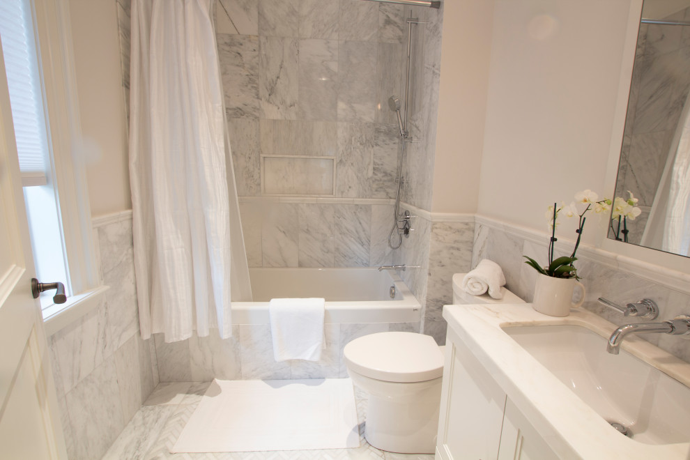 Design ideas for a mid-sized traditional 3/4 bathroom in Toronto with shaker cabinets, white cabinets, a drop-in tub, a shower/bathtub combo, a one-piece toilet, white tile, marble, white walls, marble floors, an undermount sink, marble benchtops, white floor, a shower curtain, white benchtops, a niche, a single vanity and a built-in vanity.