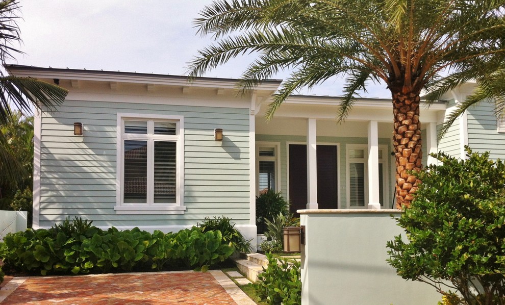 This is an example of a tropical one-storey green exterior in Miami with wood siding.