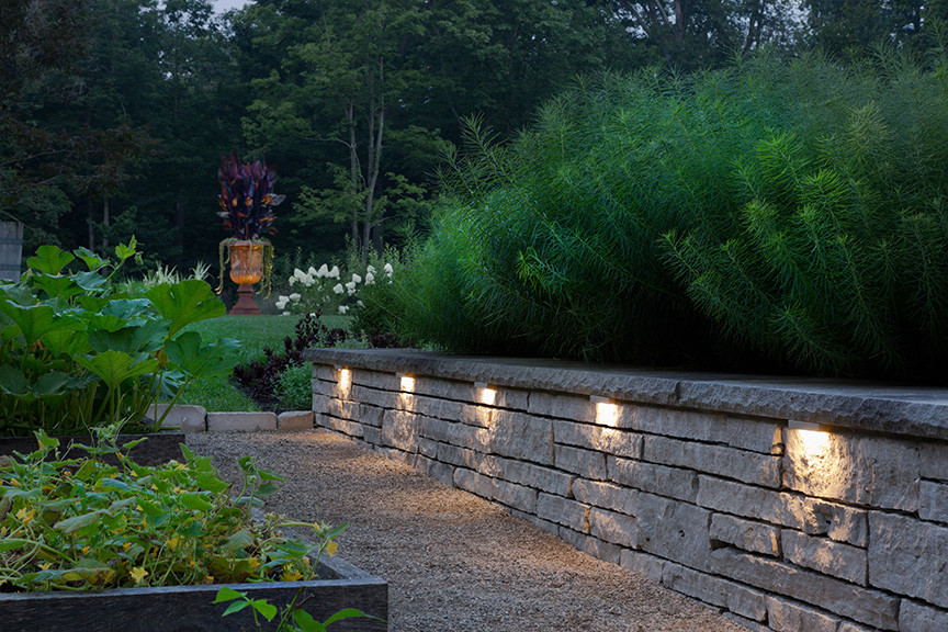 This is an example of a large traditional backyard garden in Cleveland with a retaining wall and gravel.