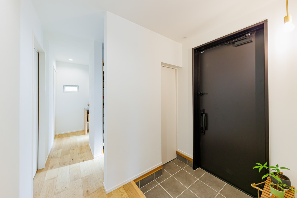 Imagen de hall blanco minimalista de tamaño medio con paredes blancas, puerta simple, puerta negra, papel pintado y papel pintado