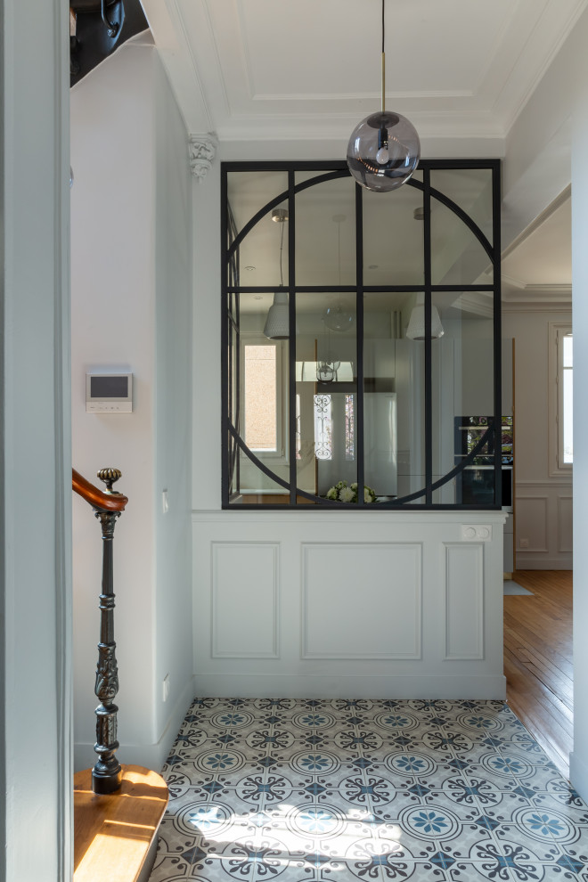 Large foyer in Paris with grey walls, ceramic floors, a double front door, a white front door, multi-coloured floor, recessed and decorative wall panelling.