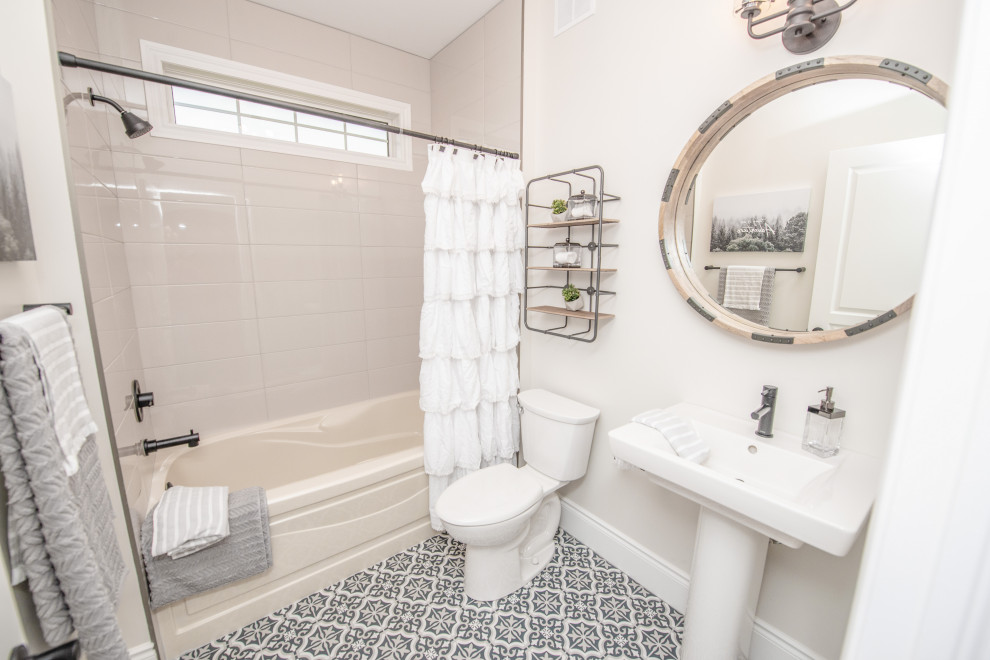 Photo of a mid-sized transitional 3/4 bathroom in Other with ceramic floors, a pedestal sink, blue floor, a drop-in tub, an alcove shower, a one-piece toilet, white walls, a shower curtain, beige tile and ceramic tile.
