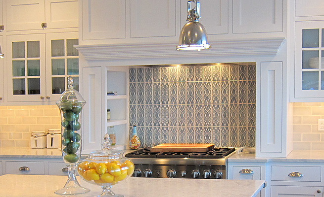 Example of a mid-sized transitional u-shaped enclosed kitchen design in Orange County with glass-front cabinets, white cabinets, marble countertops, blue backsplash, ceramic backsplash, stainless steel appliances and an island