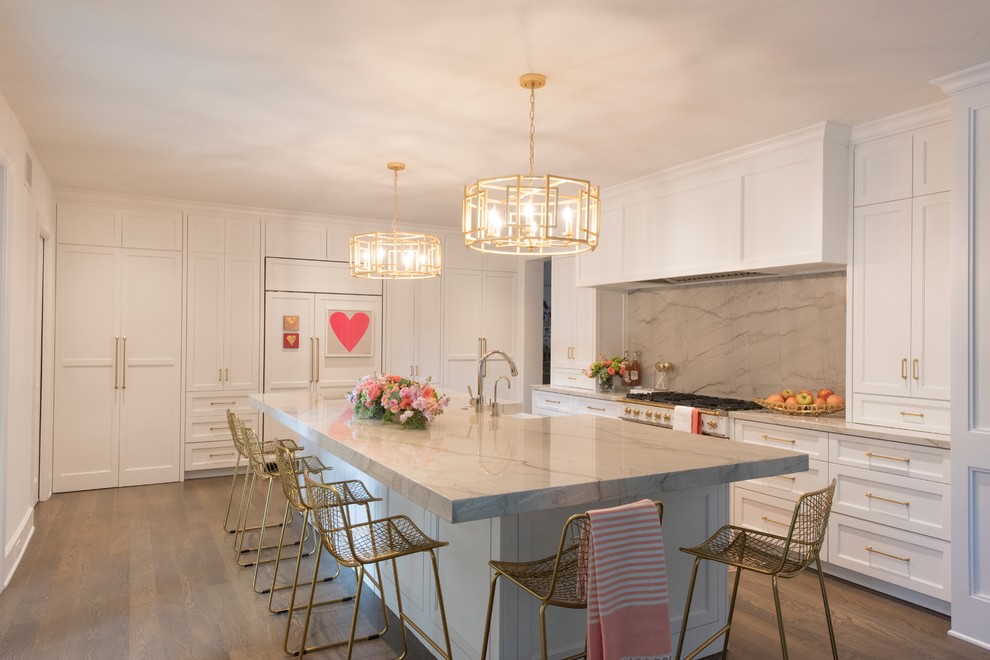 Example of a large transitional l-shaped medium tone wood floor and brown floor open concept kitchen design with a farmhouse sink, recessed-panel cabinets, white cabinets, quartzite countertops, white backsplash, stone slab backsplash, paneled appliances and an island