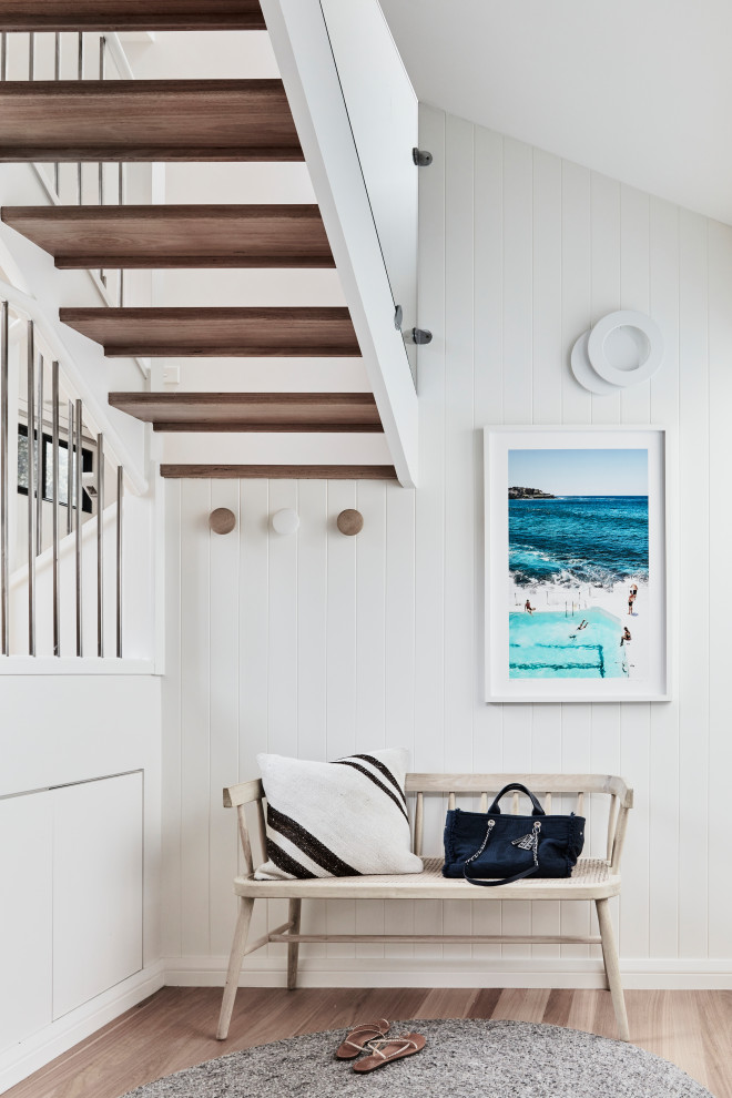 Photo of a small beach style foyer in Sydney with white walls, light hardwood floors, a single front door, a glass front door and planked wall panelling.