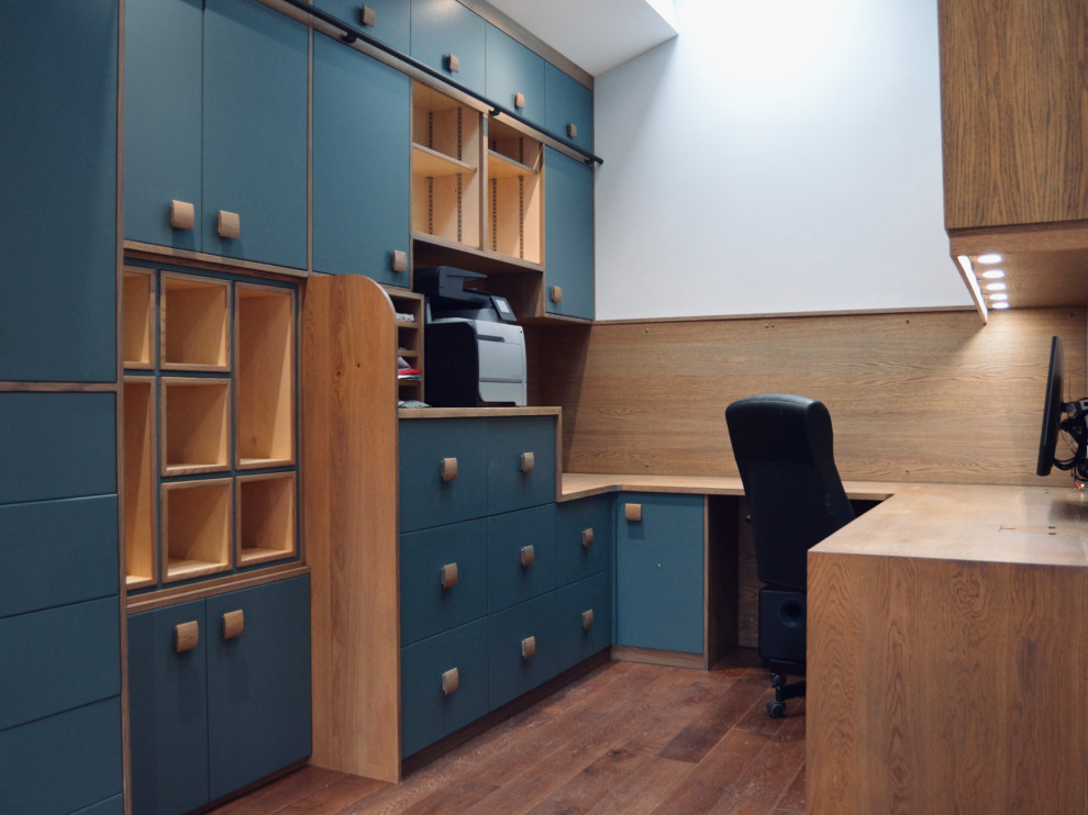 Ejemplo de despacho actual de tamaño medio con paredes blancas, suelo de madera oscura, escritorio empotrado y suelo marrón