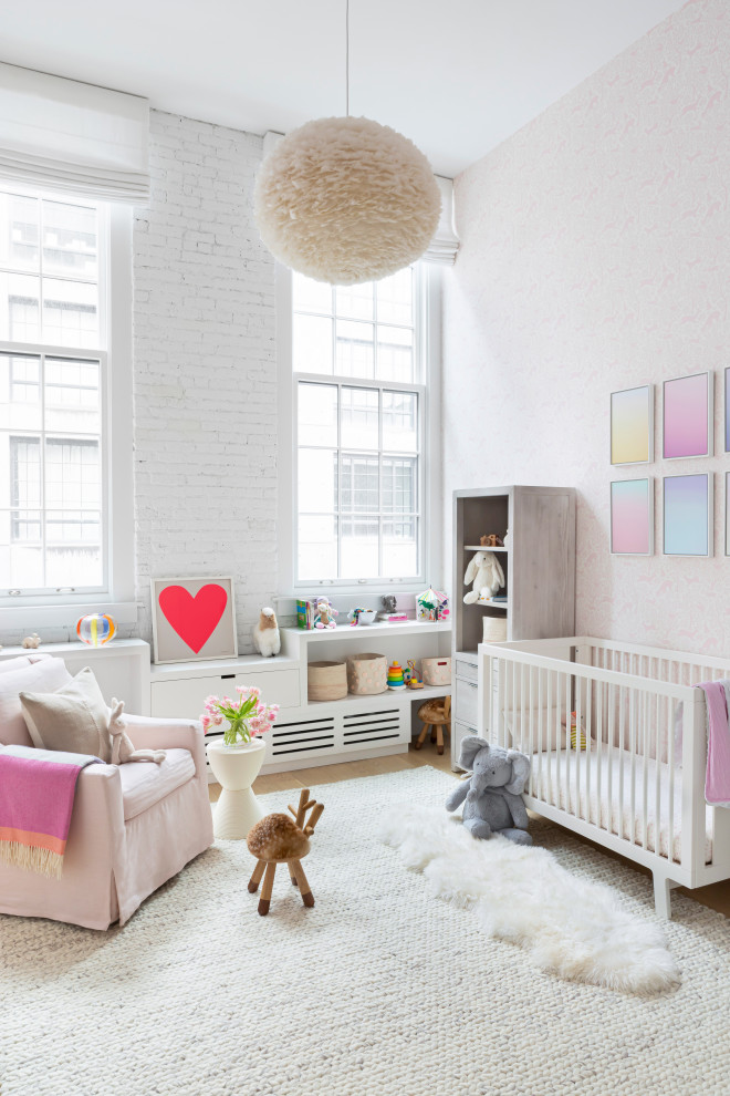 Large contemporary nursery in New York with white walls, light hardwood floors and brown floor for girls.