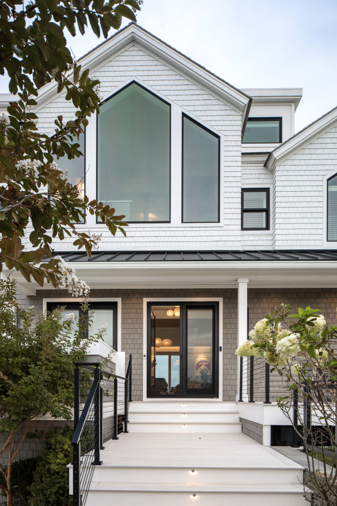 Идея дизайна: двухэтажный, разноцветный частный загородный дом среднего размера в морском стиле с облицовкой из бетона, полувальмовой крышей и отделкой дранкой