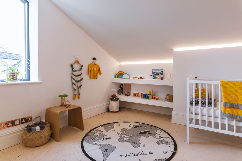 Photo of a large contemporary gender-neutral nursery in Manchester with white walls and light hardwood floors.