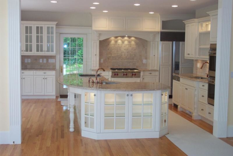 Design ideas for a large traditional u-shaped eat-in kitchen in Boston with white cabinets, beige splashback, stainless steel appliances, light hardwood floors, with island, a drop-in sink and louvered cabinets.