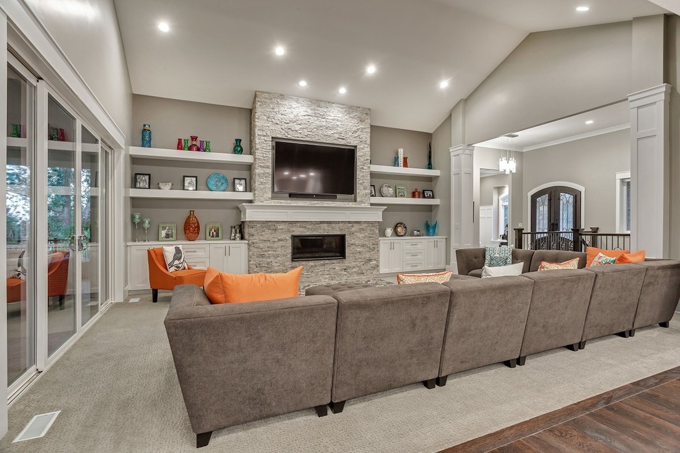 This is an example of a large arts and crafts open concept family room in Salt Lake City with grey walls, carpet, a standard fireplace, a stone fireplace surround, a wall-mounted tv and grey floor.