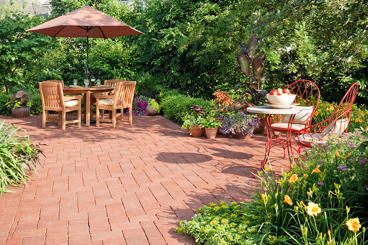 This is an example of a large traditional backyard patio in Chicago with a container garden, brick pavers and a roof extension.