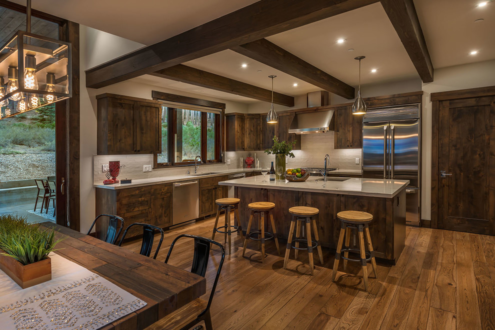 Design ideas for a country l-shaped eat-in kitchen in Sacramento with an undermount sink, shaker cabinets, dark wood cabinets, grey splashback, stainless steel appliances, dark hardwood floors, with island, brown floor and grey benchtop.