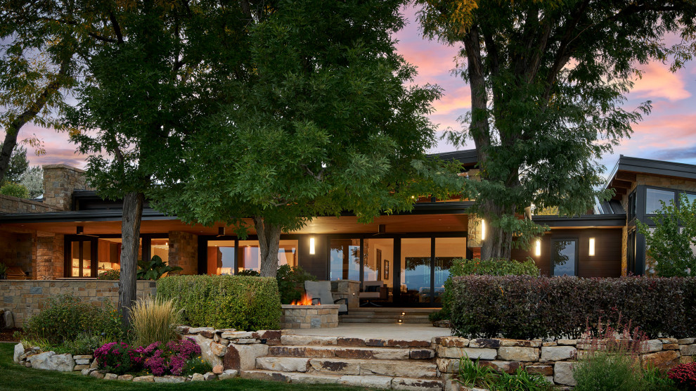 Inspiration for a large contemporary backyard stone patio remodel in Denver with a fire pit and a roof extension