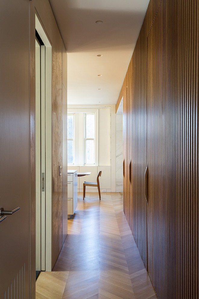 Photo of a mid-sized modern hallway in New York with white walls and light hardwood floors.
