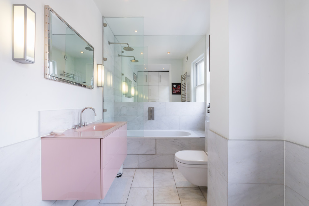 Inspiration for a contemporary bathroom in London with multi-coloured tile, flat-panel cabinets, a corner tub, a shower/bathtub combo, a wall-mount toilet, white walls, marble floors, a wall-mount sink and grey floor.