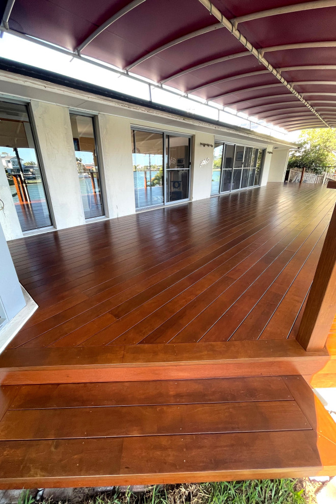 Ejemplo de terraza planta baja extra grande en patio trasero con toldo y barandilla de madera