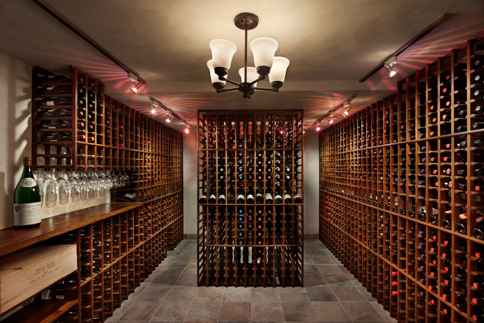 This is an example of an expansive country wine cellar in New York with slate floors and display racks.
